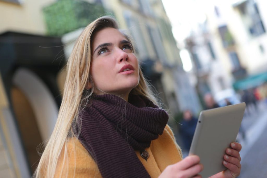 Photo of woman using tablet outdoors and looking up